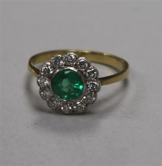 A modern 18ct gold, emerald and diamond circular cluster ring, size N.